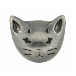 Pode incluir: Um botão de metal prateado em forma de rosto de gato. O gato tem olhos pretos, nariz preto e bigodes pretos.