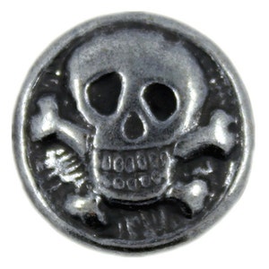 May include: A silver-toned metal button with a skull and crossbones design. The skull has black eye sockets and a detailed mouth.