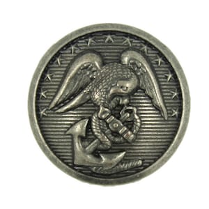 May include: A circular, antique silver button with an eagle, anchor, and stars design. The button has a detailed, textured surface. Ideal for sewing or craft projects. The button's diameter is approximately 2.5 cm.