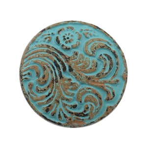 May include: A round, turquoise blue knob with a distressed finish. The knob features a raised, intricate design of swirls and floral patterns in shades of brown and black.