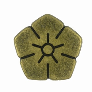 Puede incluir: Un botón de metal dorado en forma de flor con un contorno negro y un pequeño círculo en el centro.