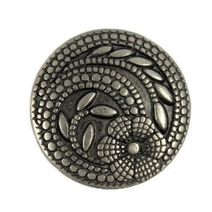 May include: A silver-toned metal button with a floral design. The button features a raised flower with a textured center and leaves surrounding it. The button is decorated with a repeating pattern of small dots.