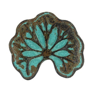 Peut inclure: Une pièce décorative en métal bleu turquoise et marron en forme de fleur avec un bord festonné.