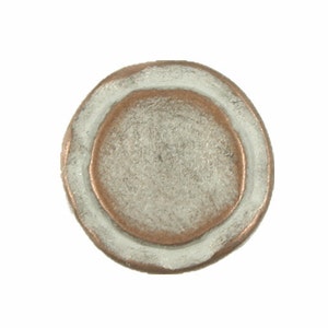 May include: A round, white ceramic coaster with a copper-colored center. The coaster has a raised edge and a slightly distressed finish.