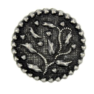 May include: A silver-toned metal button with a decorative floral design. The button has a beaded edge and a textured surface.