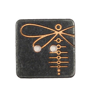 Puede incluir: Un botón cuadrado negro con un diseño de libélula de color cobre. La libélula tiene un cuerpo largo con una serie de círculos y líneas. El botón tiene dos agujeros blancos para coser.