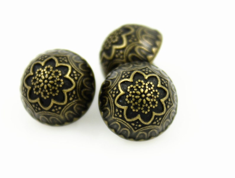 May include: Three antique gold-toned metal buttons with a decorative floral design.