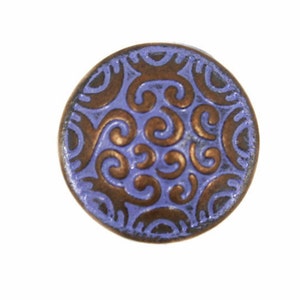 May include: A round, decorative button with a bronze-colored, swirling pattern on a periwinkle background. The button has a slightly raised design and a metallic finish. This button is suitable for sewing projects and crafts.
