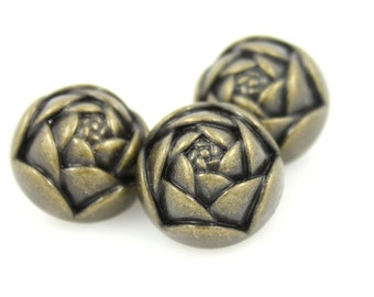 May include: Three antique gold-toned buttons with a raised floral design. The buttons are round and have a textured surface.