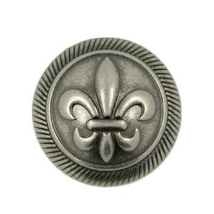 May include: A silver-toned metal button with a raised fleur-de-lis design. The button has a textured, ridged edge.