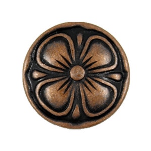 May include: A round, copper-colored button with a black floral design. The button has a raised center and a slightly textured surface.