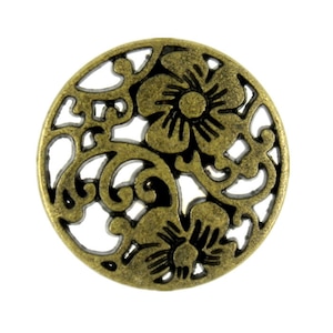 May include: A round, antique brass-colored metal embellishment with a floral filigree design. The openwork pattern features two prominent flowers and swirling vines. The decorative element is isolated on a white background.