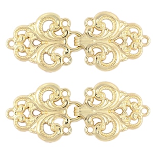 Puede incluir: Dos cierres decorativos de metal dorado con intrincados diseños florales. Cada cierre tiene un bucle a cada lado y una pieza de conexión en el centro.