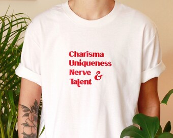 Puede incluir: Camiseta blanca con texto rojo que dice "Charisma Uniqueness Nerve & Talent".