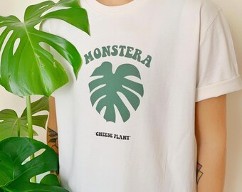 Puede incluir: Camiseta blanca con un gráfico de hoja de Monstera verde y el texto "Monstera" y "Cheese Plant".