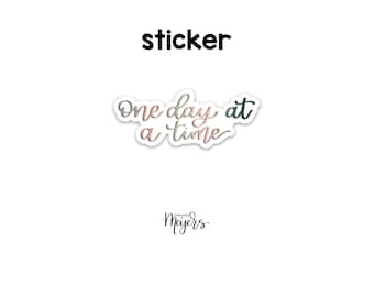 May include: A sticker with the text "One day at a time" in a pink and green gradient font. The sticker is from the company "moments by Meyers".