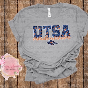 May include: A heather gray t-shirt featuring the text "UTSA roadrunners" in blue and orange. The word "UTSA" has a leopard print design. A logo of a roadrunner bird is below the text.