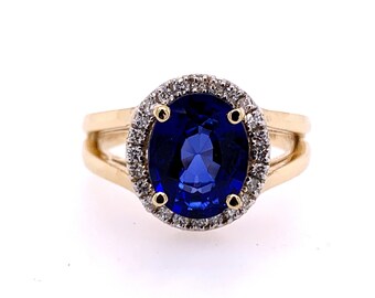 Op de afbeelding: Een gouden ring met een grote ovale blauwe saffier omringd door een halo van kleinere diamanten.