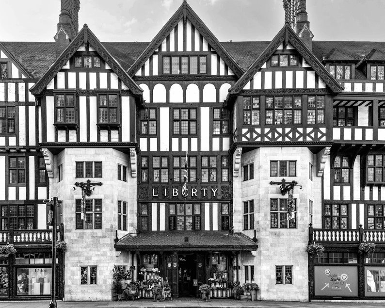 May include: A black and white photo of a building with a sign that reads "LIBERTY". The building has a Tudor style architecture with a lot of intricate details.