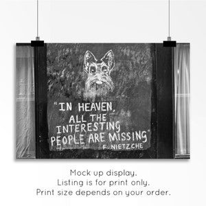 May include: Black and white photo of a wall with a quote by Friedrich Nietzsche, "In heaven, all the interesting people are missing." The quote is written in white chalk and a drawing of a dog is above the quote.