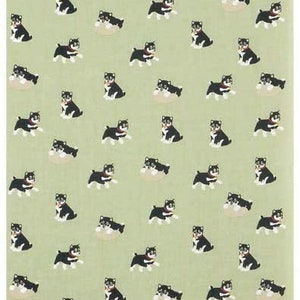 May include: A green fabric with a repeating pattern of black and white dogs. The dogs are in various poses, some are sitting, some are standing, and some are running. The fabric is a light green color and the dogs are a dark black color.