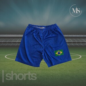 May include: Blue shorts with the Brazilian flag patch on the right leg. The shorts have an elastic waistband and are made of a lightweight material. The word "shorts" is printed at the bottom of the image.
