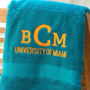 May include: A teal blue towel with the embroidered text "BCM UNIVERSITY OF MIAMI" in orange.