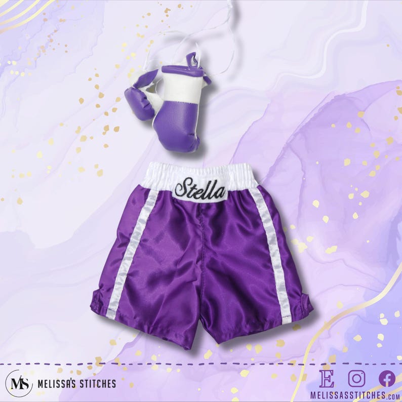 K&ouml;nnte beinhalten: Lilafarbene Boxershorts aus Satin mit wei&szlig;em Besatz und dem Namen "Stella" auf der Taille gestickt. Die Shorts werden mit einem Paar lila und wei&szlig;en Boxhandschuhen geliefert.