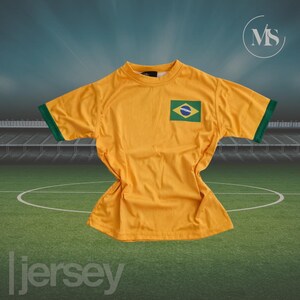 May include: A yellow jersey with green trim on the sleeves and a Brazilian flag patch. The jersey is displayed on a green field with a soccer pitch design. The word "jersey" is printed at the bottom.