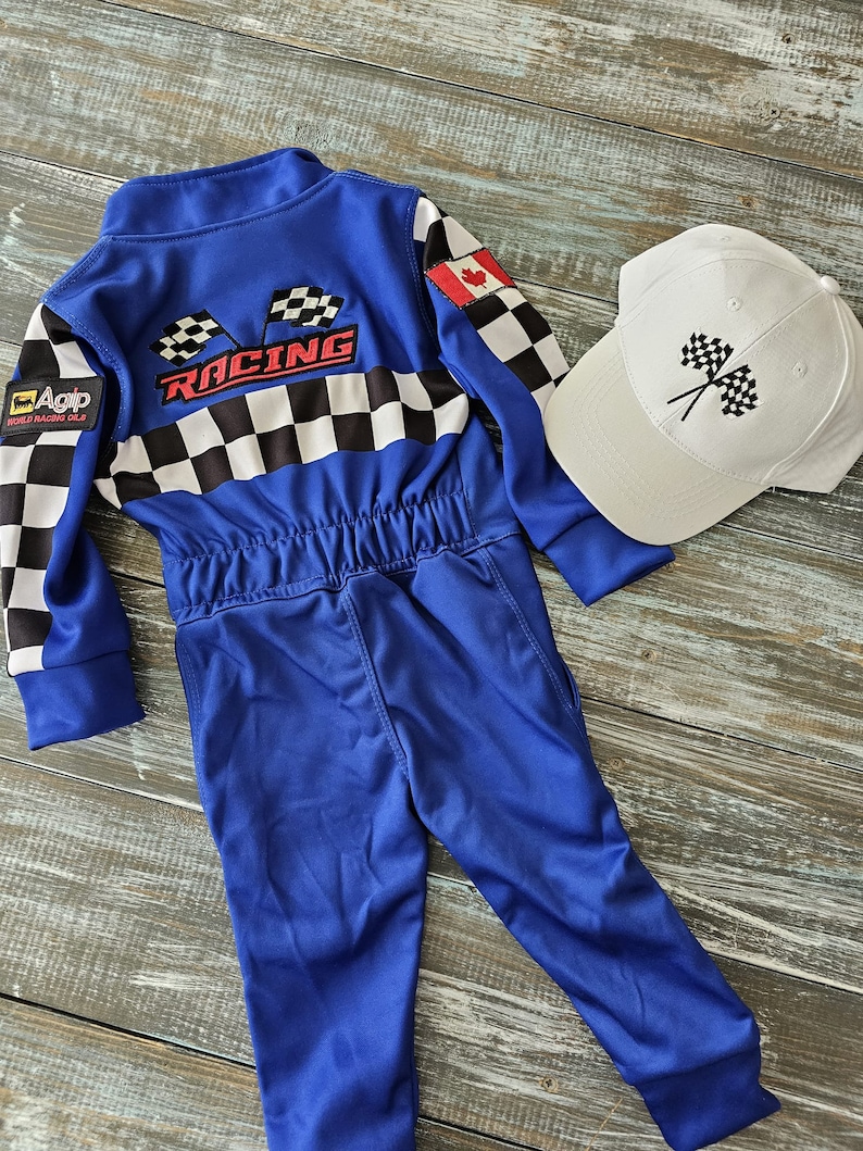 K&ouml;nnte beinhalten: Blauer Rennanzug mit kariertem Muster und dem Wort "Racing" auf dem R&uuml;cken. Der Anzug hat einen kanadischen Flaggen-Patch auf der Schulter. Eine wei&szlig;e Baseballkappe mit einem karierten Flaggenmuster ist im Lieferumfang enthalten.