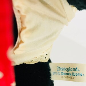 K&ouml;nnte beinhalten: Schwarzes Pl&uuml;schtier mit wei&szlig;em Spitzenbesatz und einem roten Stoffdetail. Das Spielzeug hat ein Etikett mit der Aufschrift "Disneyland Walt Disney World &copy;DISNEY".
