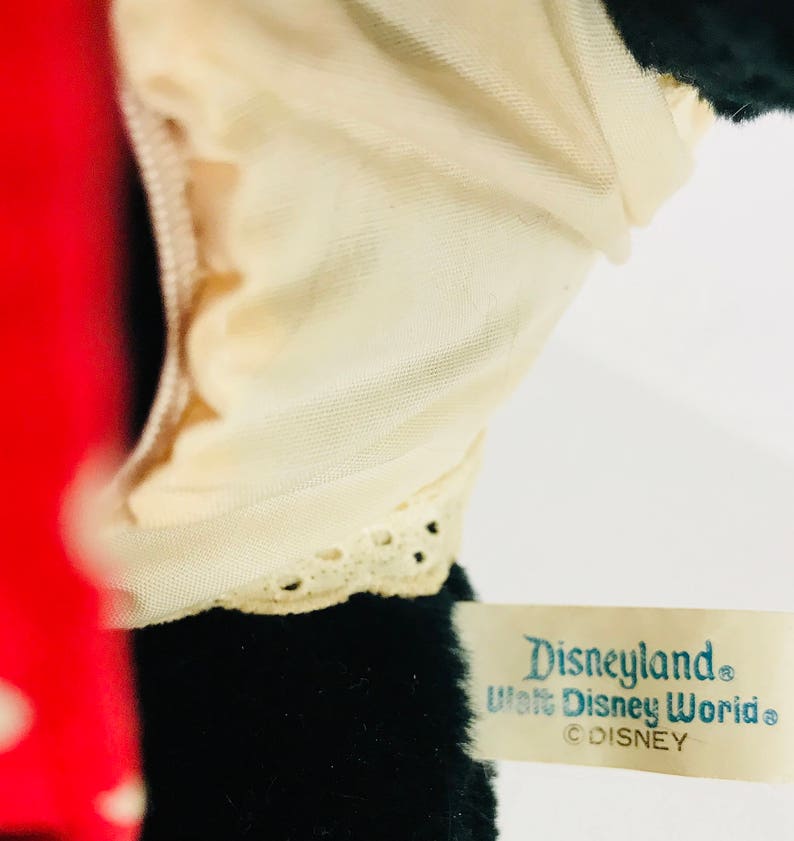 K&ouml;nnte beinhalten: Schwarzes Pl&uuml;schtier mit wei&szlig;em Spitzenbesatz und einem roten Stoffdetail. Das Spielzeug hat ein Etikett mit der Aufschrift "Disneyland Walt Disney World &copy;DISNEY".