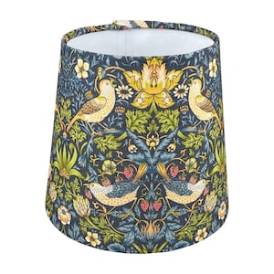 May include: A cylindrical lampshade with a detailed floral and bird pattern. The design features yellow birds, red berries, and green foliage against a dark blue background. The lampshade has a white interior and a fabric exterior.