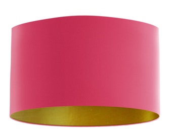 May include: A pink lampshade with a gold lining. The lampshade is cylindrical and has a smooth surface.