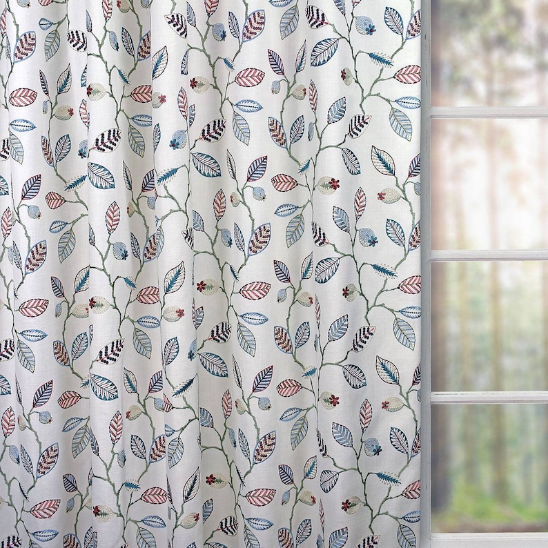 May include: White fabric with a repeating pattern of blue, green, and red leaves on a white background. The leaves are stylised and have a whimsical design.