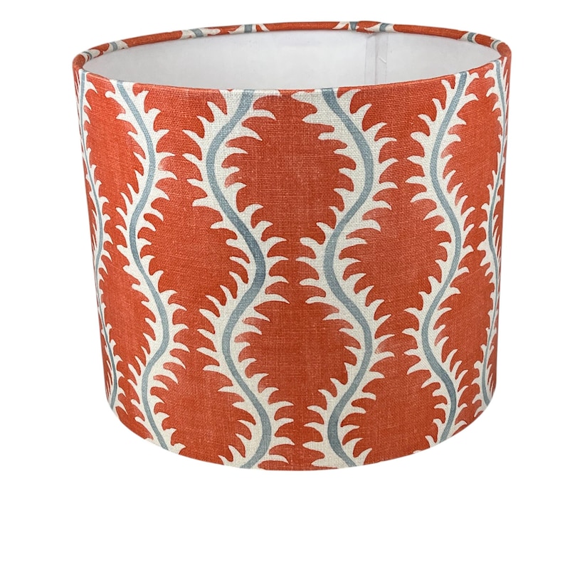 May include: A red and blue patterned lampshade with a white lining. The pattern features a repeating wave design with a blue outline.