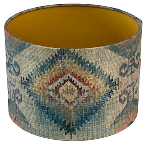 May include: A cylindrical lampshade with a geometric pattern in shades of blue, red, and brown. The inside of the lampshade is lined with a solid yellow fabric.