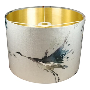 May include: A white drum lampshade with a gold interior and a watercolor design of birds in flight.