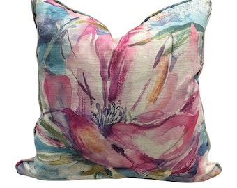 May include: Square decorative pillow with a watercolor floral design. The pillow features a large pink flower with purple and orange accents against a light blue and white background. The pillow has a light blue border.