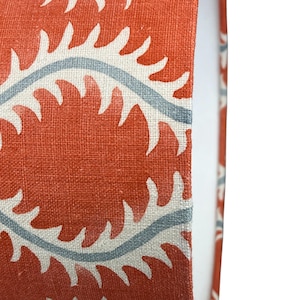 May include: Close-up of a red and white fabric with a pattern of stylized leaves. The fabric has a textured surface and a subtle sheen.