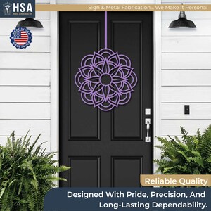 Purple metal mandala door wreath hanging on a black front door; geometric garden art for year-round front door decor.