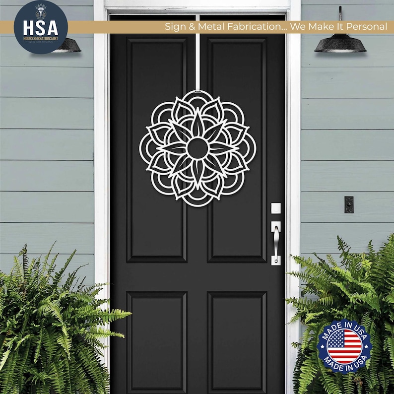 White metal mandala door wreath on a black front door; geometric floral wall art for outdoor front door decor.