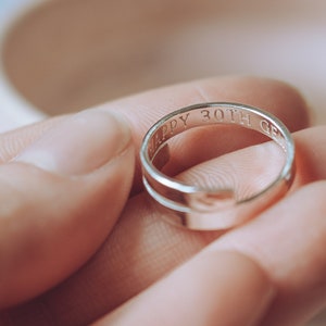 May include: A silver ring inscribed with "Happy 30th" on a finger.