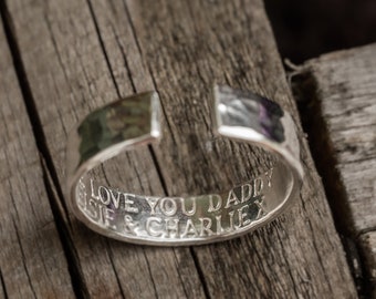 May include: Silver ring with a hammered finish and an inscription that reads "Love you Daddy Elsie & Charlie X".