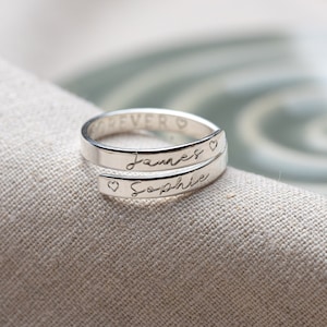 May include: A silver ring engraved with the names "James" and "Sophie", separated by a heart symbol.