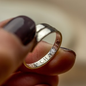 May include: A silver ring with the inscription "CHARLIE" engraved on the inside band.
