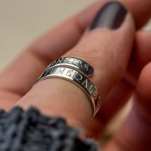 May include: A silver ring with the words "FUNERALS" and "ONE" engraved on it.