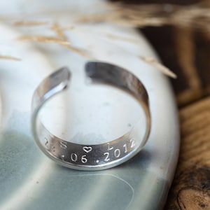 May include: A silver ring with an inscription that reads "S &hearts; L 28.06.2012".