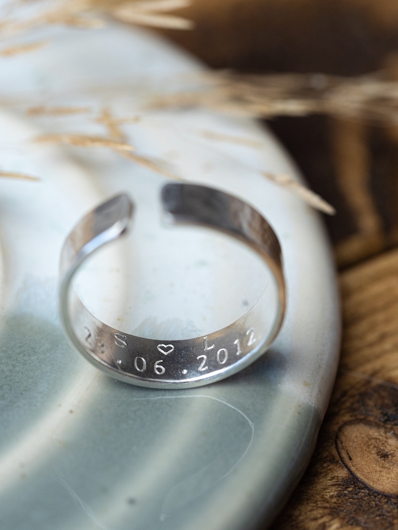 May include: A silver ring with an inscription that reads "S &hearts; L 28.06.2012".