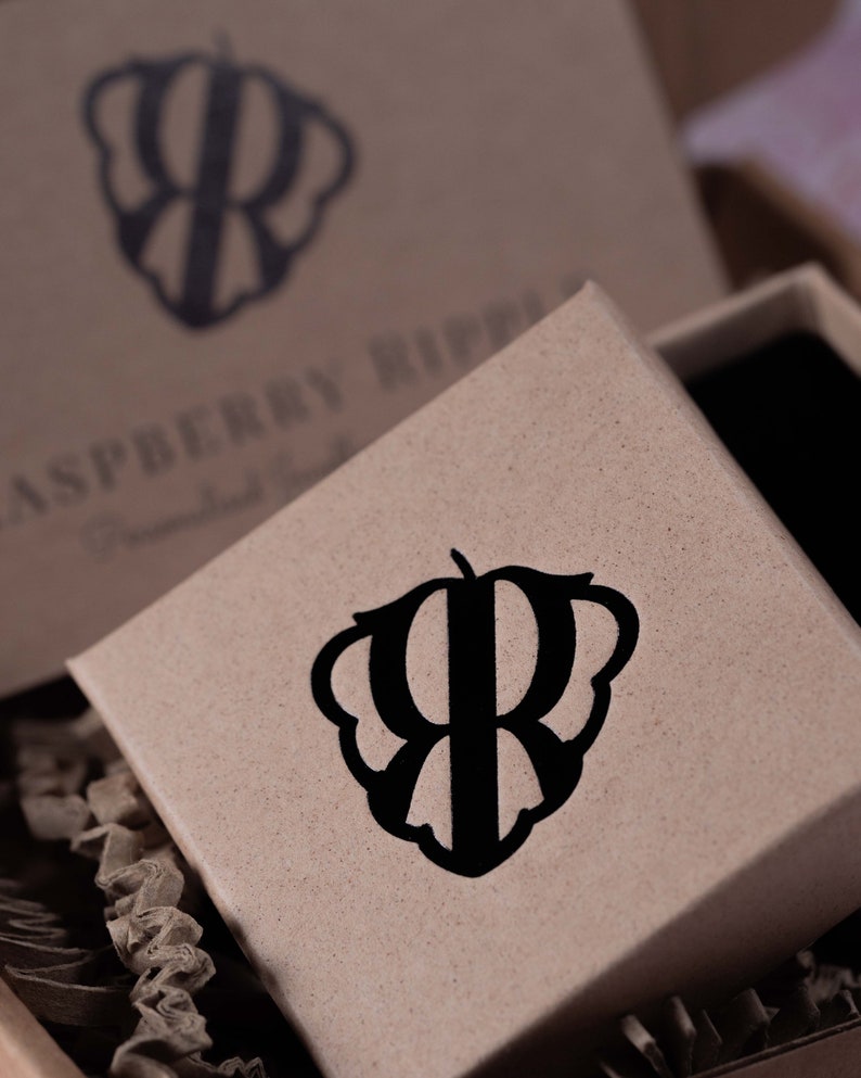 May include: A brown cardboard box with a black logo of a stylized raspberry with the letter "R" inside. The text "Raspberry Ripple" is printed on the box.